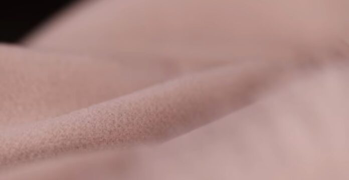 A close-up of soft, light-pink fleece or fabric with a plush texture, suggesting a warm winter coat material.Arctic Cool Performance Fabric: