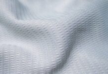 Ice Flow Athletic Fabric: Stay Cool During Intense Workouts Close-up of soft, light-gray knit fabric with tight stitching, labeled “Maximum Warmth Winter Coat.”Ice Flow Athletic Fabric:
