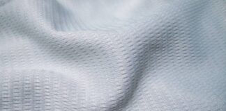 Ice Flow Athletic Fabric: Stay Cool During Intense Workouts Close-up of soft, light-gray knit fabric with tight stitching, labeled “Maximum Warmth Winter Coat.”Ice Flow Athletic Fabric: