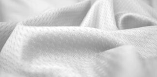 Breeze Weave Athletic Fabric: Cool Comfort, Peak Performance A close-up, grayscale image showing soft, textured fabric with folds and gentle shadows, emphasizing the fabric’s weave and plush surface.Breeze Weave Athletic Fabric: