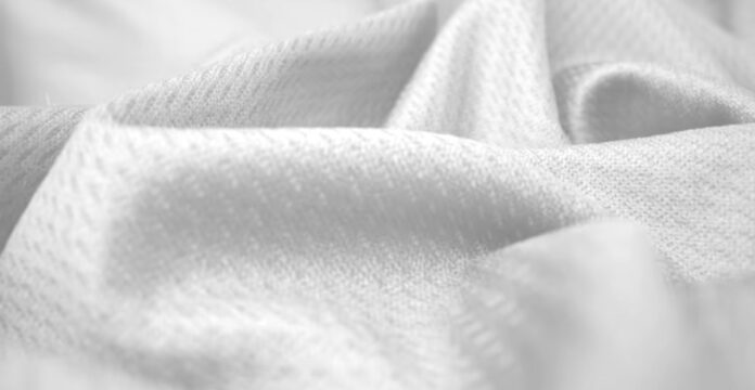 A close-up, grayscale image showing soft, textured fabric with folds and gentle shadows, emphasizing the fabric’s weave and plush surface.Breeze Weave Athletic Fabric: