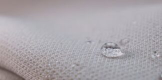 Chill Pro Moisture-Wicking Fabric Explained: Benefits & Uses "Close-up of light gray fabric with water droplets. A large droplet in focus shows a distorted reflection of the woven texture, with several smaller droplets nearby." Chill Pro Moisture-Wicking Fabric Explained: