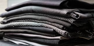 Quantum Flex Performance Fabric: Move Better, Perform Better A stack of folded dark-colored technical fabrics with textured weaves, showcasing layered materials commonly used in performance or outerwear garments.Quantum Flex Performance Fabric: