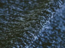 "Close-up of textured winter coat fabric showing a subtle interplay of dark and light fibers in a soft, lofty knit structure with visible depth from gentle draping." Ice Flux Performance Knit: