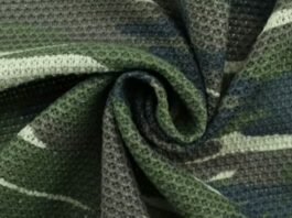 Air Weave Performance Fabric: Light Feel, Strong Performance "Close-up of flexible camouflage fabric in green, gray, and white with visible textured weave — used in a maximum-warmth winter coat." Air Weave Performance Fabric:
