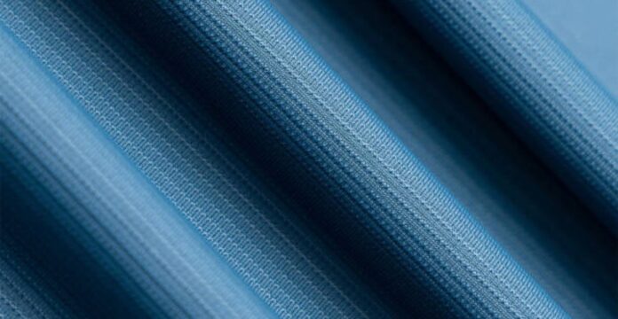 Close-up view of blue textured performance fabric with fine knit pattern, showing smooth folds and moisture-wicking material detail.Glacier Dry Performance Fabric: