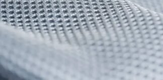 Frost Flex Cooling Fabric: Beat Heat with Smart Textiles Close-up of a light gray/white technical mesh fabric with a uniform grid of small, evenly spaced perforations; texture is sharply defined at the top and softly blurred toward the bottom. Frost Flex Cooling Fabric: