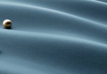 Glacier Cool Performance Fabric: Feel Cool, Stay Comfortable "Three metallic spheres — two gold, one silver — resting on softly rippled blue-gray fabric, symbolizing layered thermal regulation in the Maximum Warmth Winter Coat." Glacier Cool Performance Fabric: