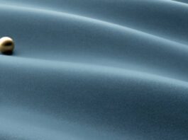 "Three metallic spheres — two gold, one silver — resting on softly rippled blue-gray fabric, symbolizing layered thermal regulation in the Maximum Warmth Winter Coat." Glacier Cool Performance Fabric: