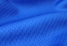 Dry Pulse Athletic Knit: Revolutionizing Sportswear Comfort "Close-up of rich navy blue textured knit fabric with visible interlocking loops and subtle dimensional folds, showing soft shadows and highlights that emphasize its thermal insulation properties." Dry Pulse Athletic Knit: