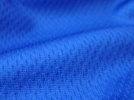 "Close-up of rich navy blue textured knit fabric with visible interlocking loops and subtle dimensional folds, showing soft shadows and highlights that emphasize its thermal insulation properties." Dry Pulse Athletic Knit: