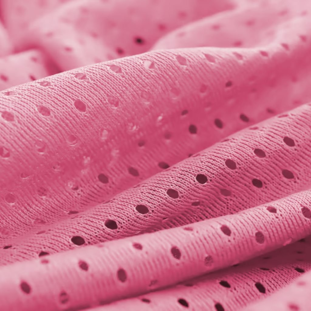 Close-up of vibrant pink fabric with a pattern of small, regularly spaced holes. The fabric is draped in soft folds, showing folds, shadows, and texture.
Cool Max Air Flow Mesh Fabric: