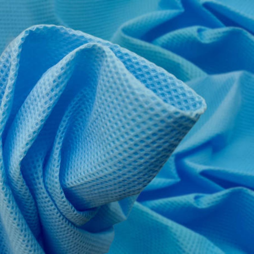 Close-up of light blue textured fabric with a waffle/honeycomb pattern, folded to create highlights and shadows.
Hydro Wick Active Fabric: