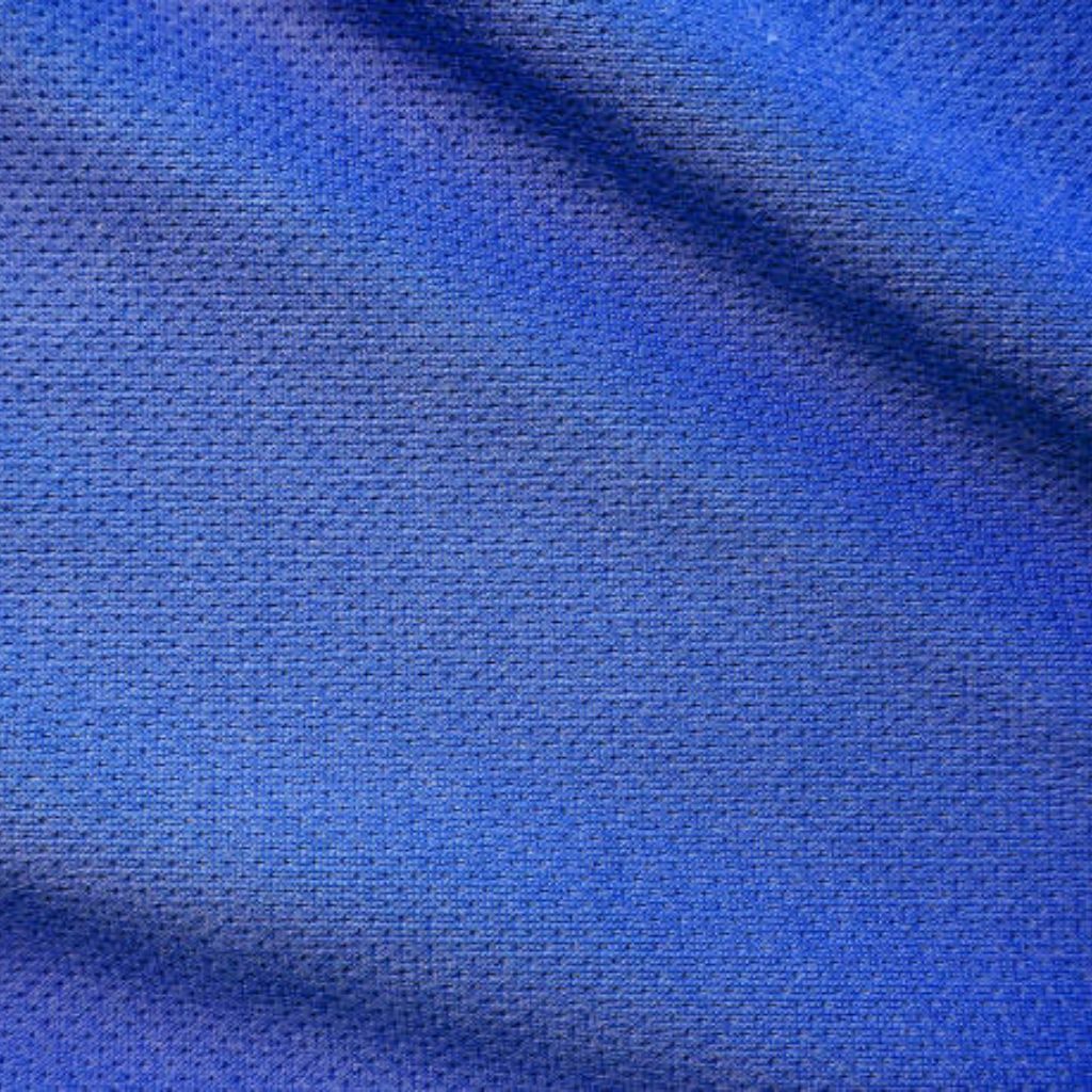 A close-up of bright orange, perforated fabric with a breathable texture. visible folds create soft shadows across the surface, highlighting the micro-dibered pattern and the contrast between smooth panels and perforations.
