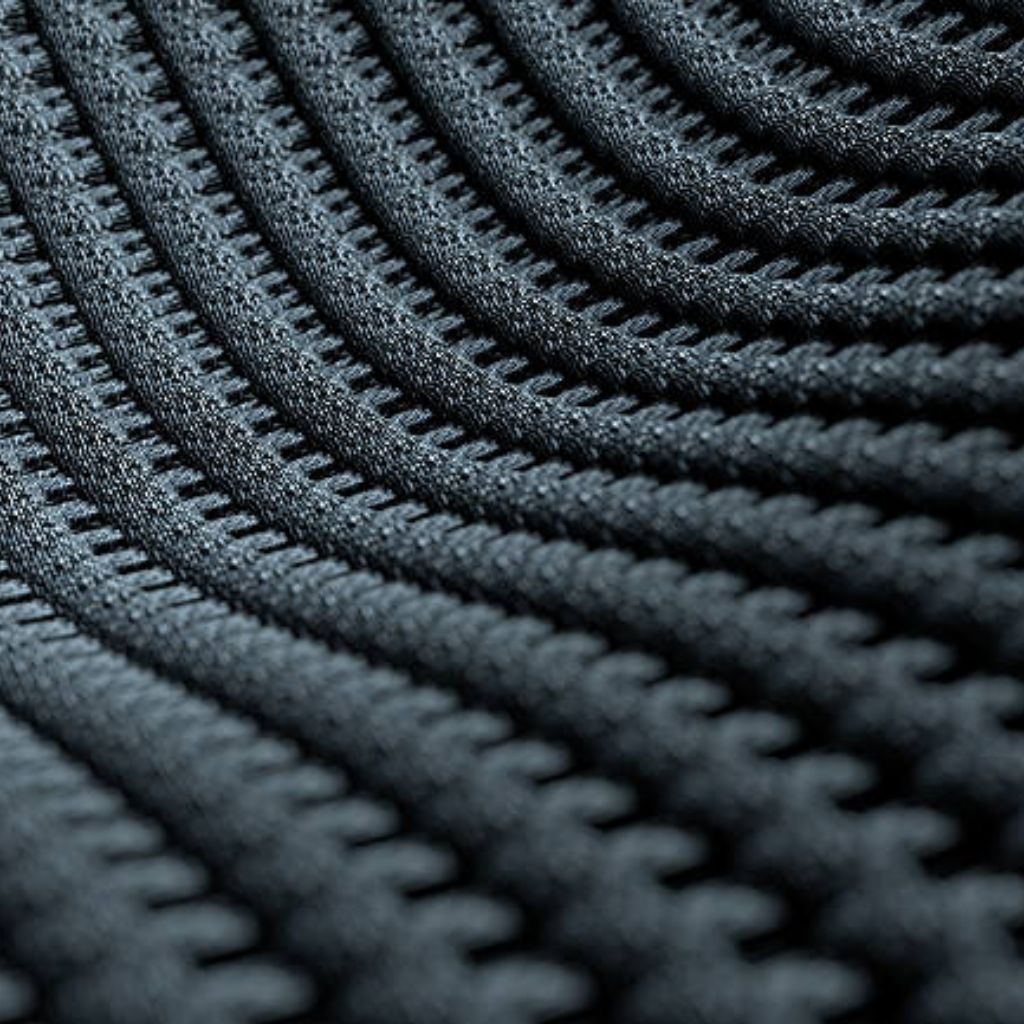 Ice Flux Performance Knit: Built for Speed, Cool & Comfort 9 "Dark gray technical knit fabric with tightly interlaced loops forming parallel, gently curved ridges that create subtle three-dimensional texture and controlled drape."
Ice Flux Performance Knit: