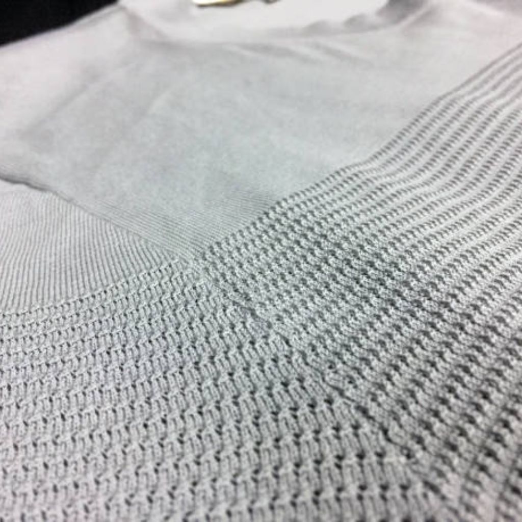 "Close-up of light gray knitted fabric with contrasting tight and open knit textures, highlighting textile craftsmanship."

Dry Pulse Athletic Knit: