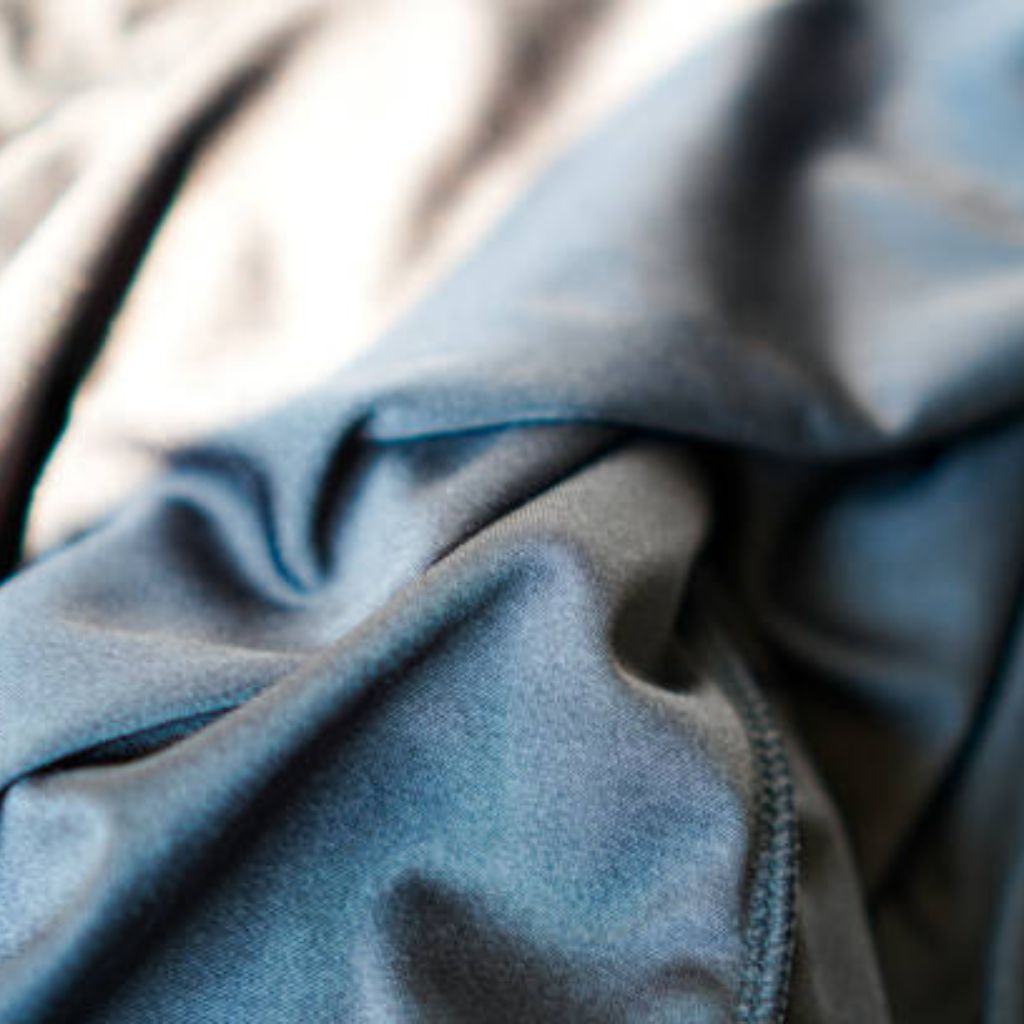Close-up of softly draped fabric in blended blue and grey tones; smooth, subtly reflective surface with gentle folds creating soft shadows and highlights.
Quantum Dry Sports Fabric
