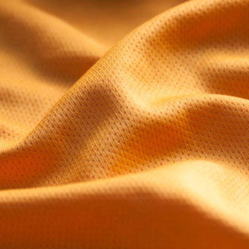 Close-up of mustard yellow breathable athletic fabric with visible weave, folds, and shadows highlighting its texture.Fresh Flow Athletic Fabric:
