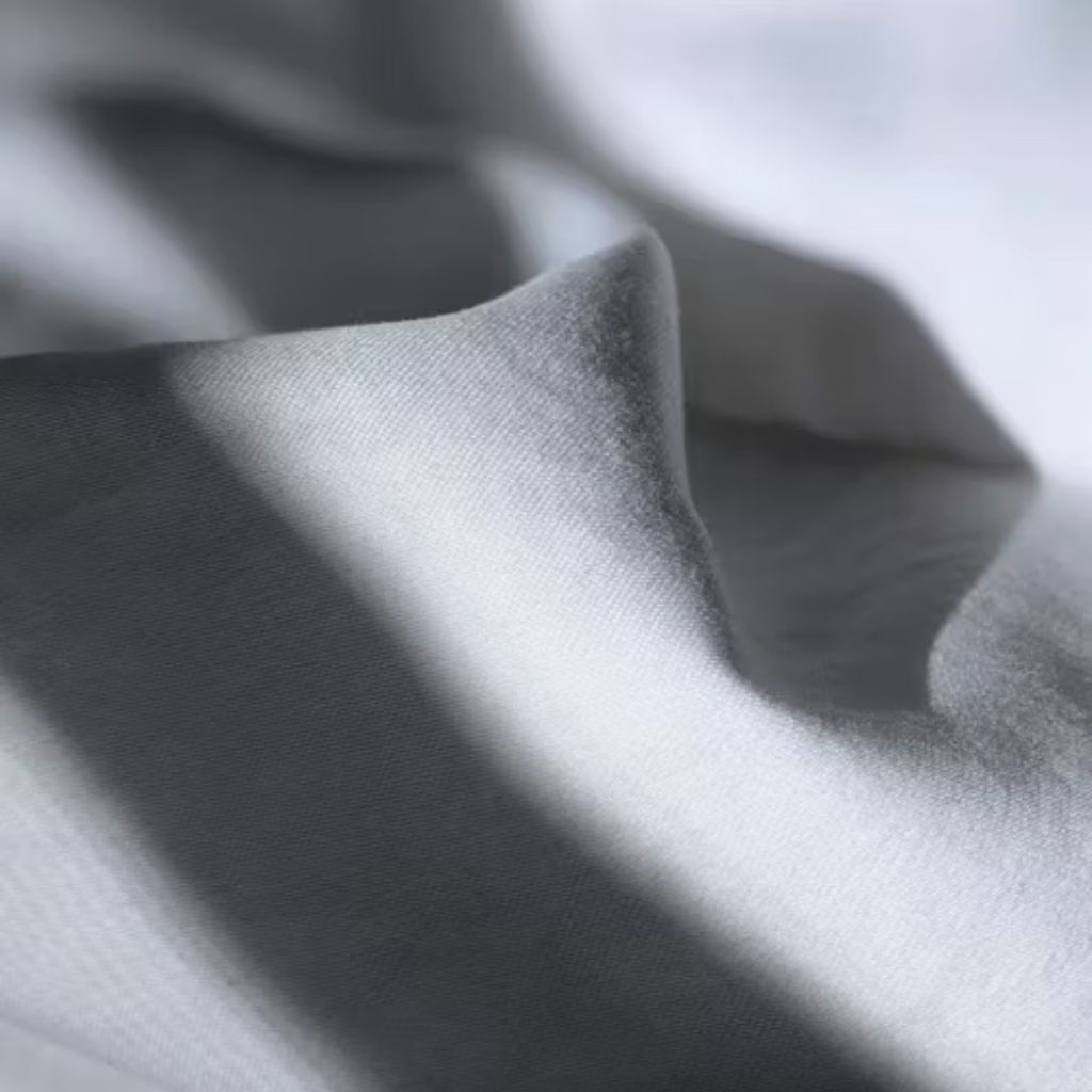 Close-up of white fabric draped in soft folds, with strong lighting creating dramatic shadows and highlights.

Power Stretch Active Fabric: