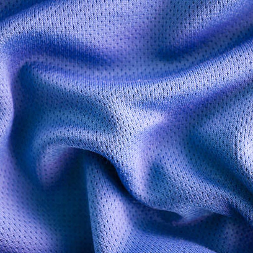 Close-up of blue and purple athletic mesh fabric with small, uniform holes and soft folds creating shadows and depth.Fresh Flow Athletic Fabric:
