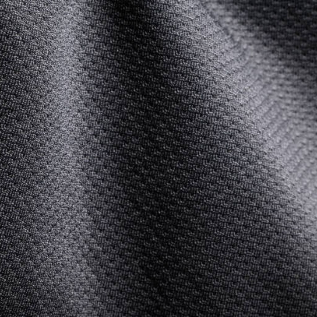 MotionX Breathable Sports Fabric: Performance Meets Comfort 10 "Close-up of dark gray textured fabric with a woven, mesh-like pattern and subtle folds creating shadows."
MotionX Breathable Sports Fabric: