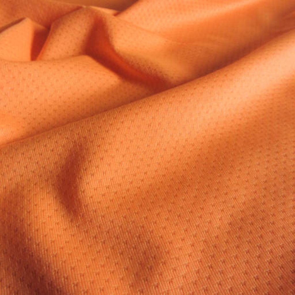 Long alt text: A close-up view of bright orange fabric with a small, evenly spaced perforation pattern, showing soft folds and a smooth, breathable texture suitable for a winter jacket.
Ventra Cool Training Fabric: