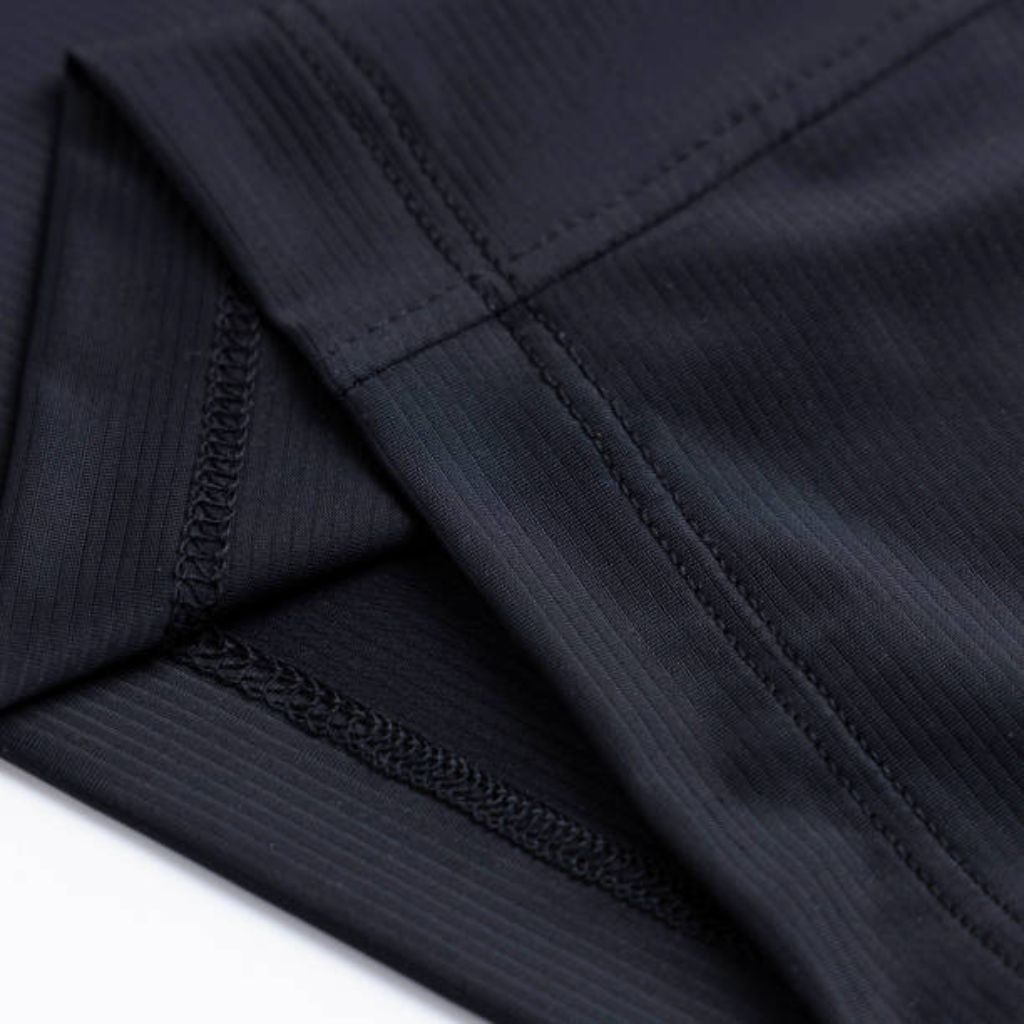 Close-up of a dark navy blue athletic shirt showing a ribbed fabric texture, visible stitched seams, and a V-shaped junction where two fabric pieces meet.
ProFit Compression Tech Fabric