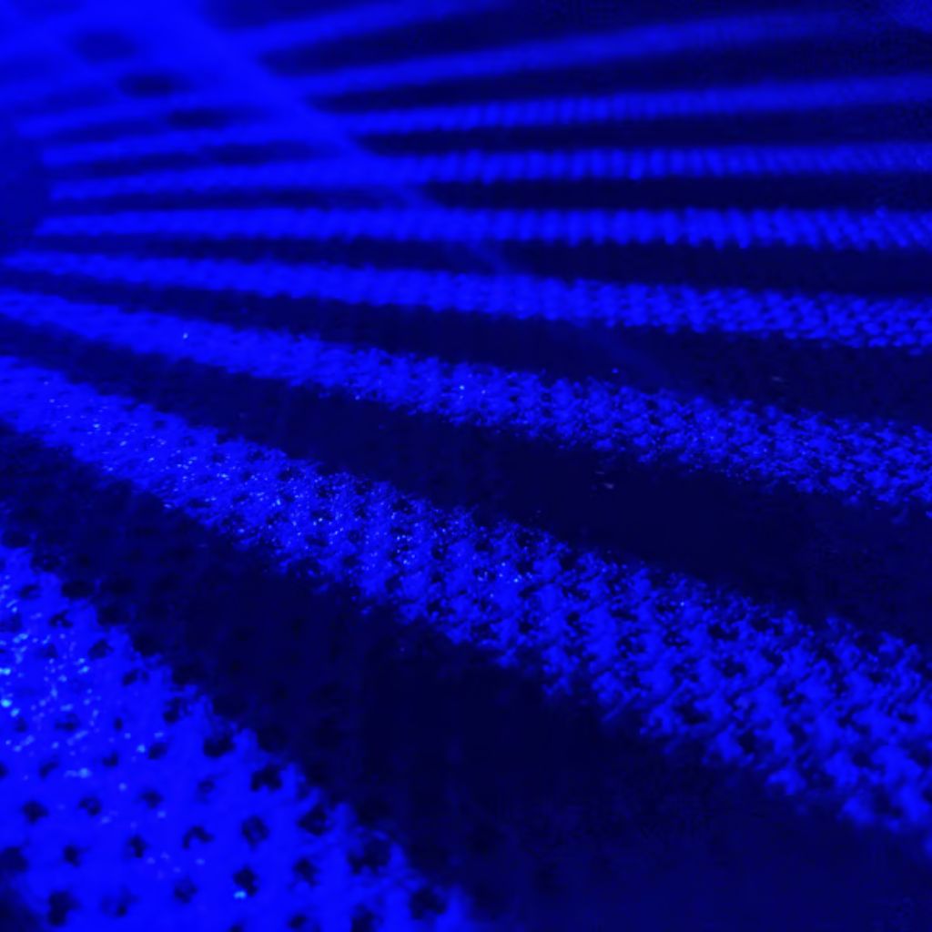 Ultra Motion Dynamic Stretch Weave: Advanced Sports Fabric 10 "Close-up abstract image of deep blue ribbed fabric with raised parallel lines and a porous, mesh-like texture, highlighted by dynamic lighting."
Ultra Motion Dynamic Stretch Weave: