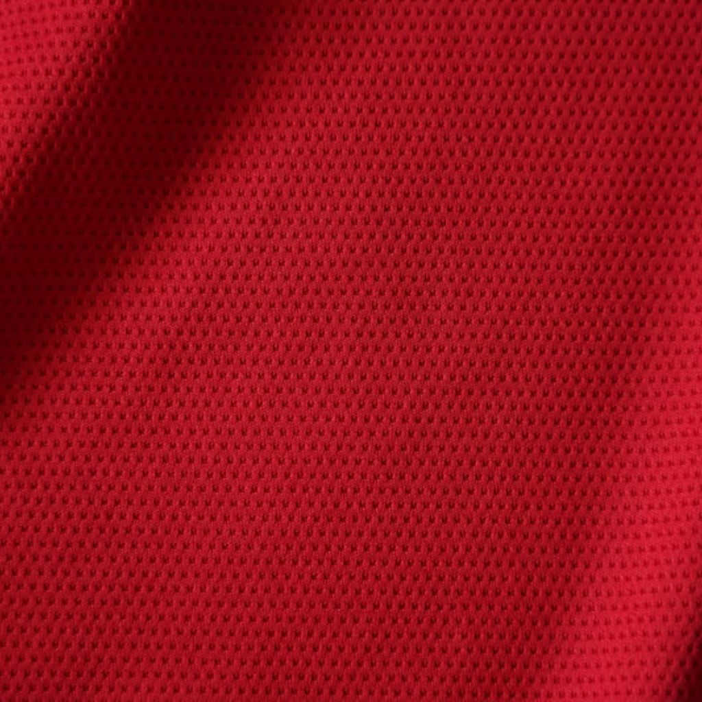 MotionX Breathable Sports Fabric: Performance Meets Comfort 11 "Close-up of red fabric with a regular dotted pattern and small perforations, showing texture and depth from lighting."
MotionX Breathable Sports Fabric: