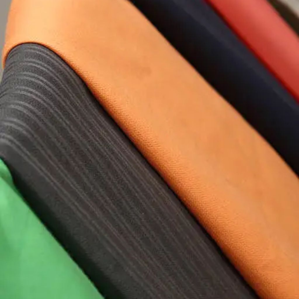 “Close-up of stacked colorful winter jackets with textures in orange, black, green, and red, showing fabric details.”
Breeze Tech Training Fabric: