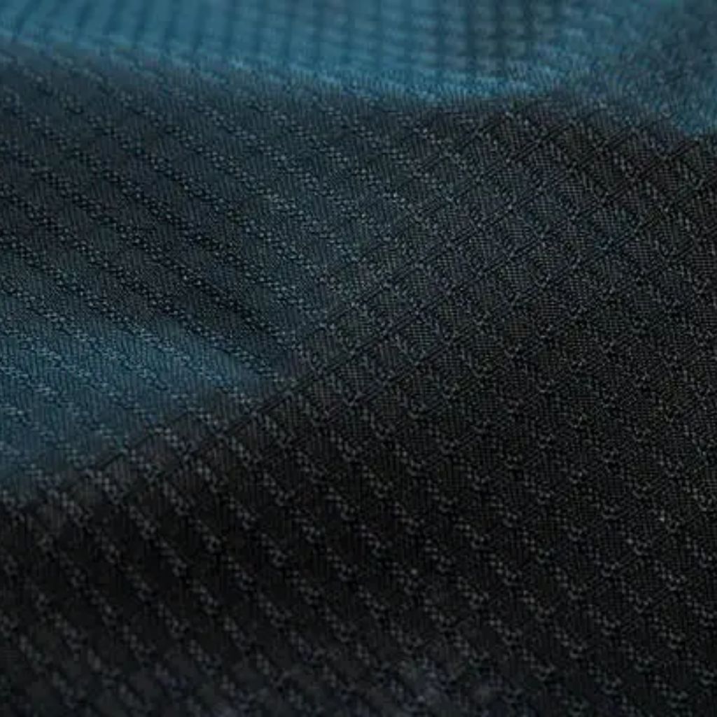 A close-up shot of dark blue and black fabric with a subtle dotted texture, showing diagonal lines and soft folds.
Vapor Flow Athletic Fabric:
