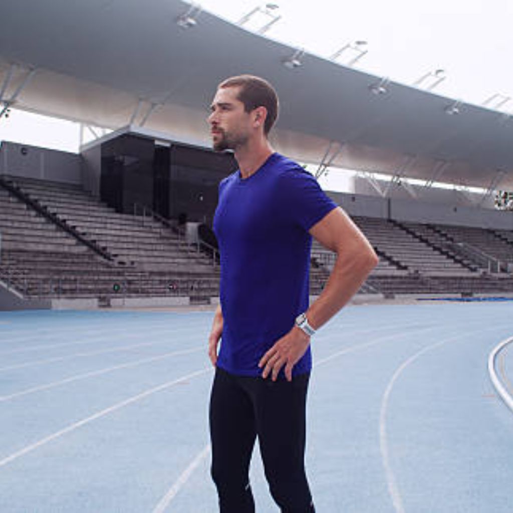 Kinetic Flow Athletic Fabric: Ultimate Comfort for Athletes 11 A man in a blue t-shirt and black leggings stands confidently on a blue running track in an outdoor stadium.
Kinetic Flow Athletic Fabric: