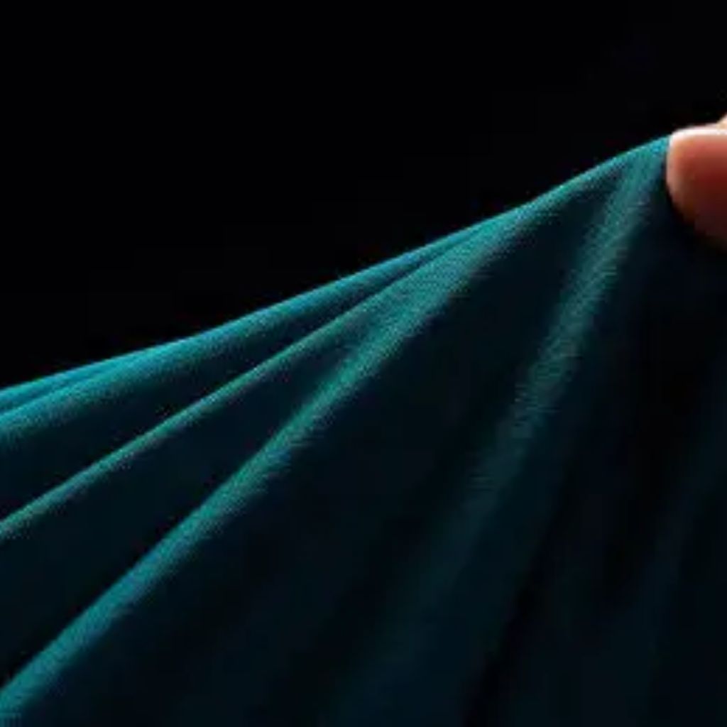 Close-up of teal fabric being held by a finger against a black background, showing draped folds, texture, and a subtle sheen.
Power Stretch Active Fabric:
