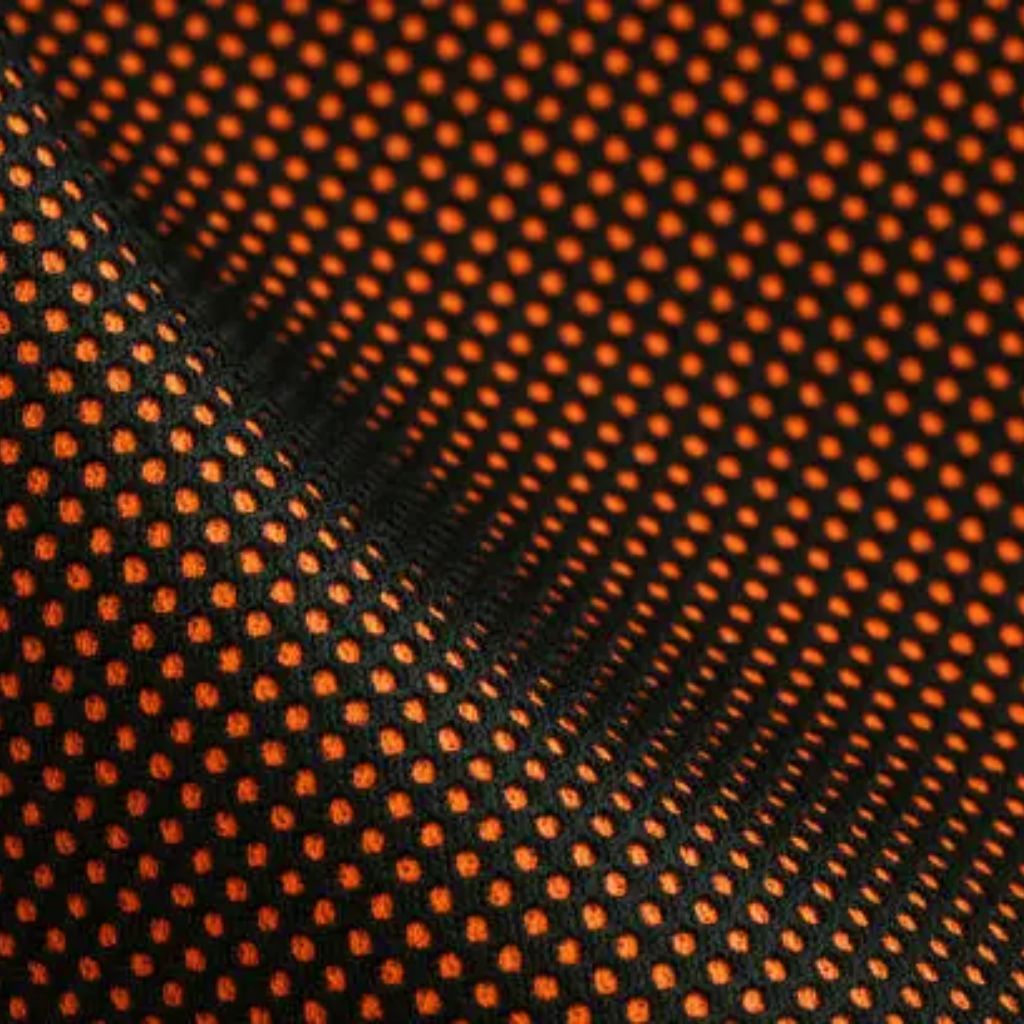 Close-up of black fabric with an evenly spaced grid of small orange dots and subtle wrinkles, suggesting a lightweight material.
Air Mesh Pro Performance Fabric: