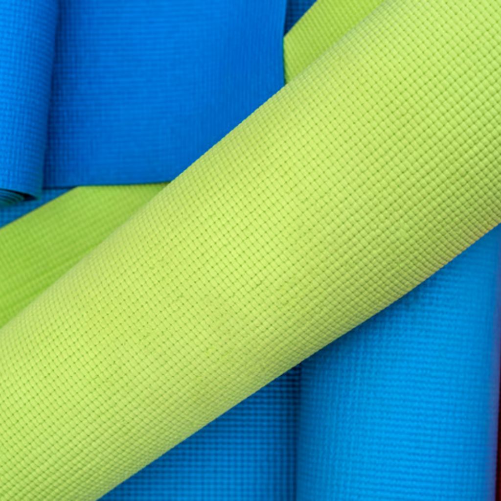 MotionX Breathable Sports Fabric: Performance Meets Comfort 7 "Close-up of rolled yoga mats in blue and green, with a prominent diagonal lime-green mat across the frame and a textured grid pattern on the surfaces."
MotionX Breathable Sports Fabric: