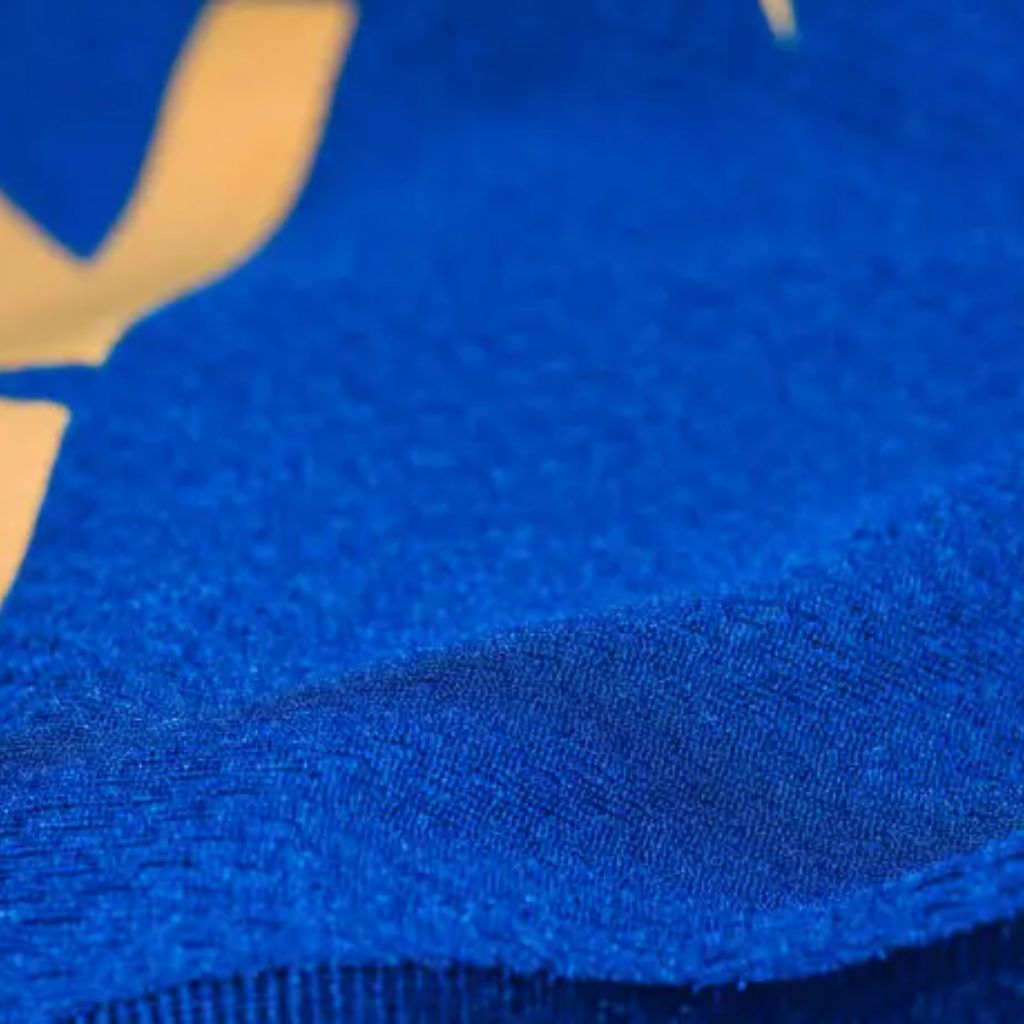 "Close-up of royal blue rippled-texture fabric with a folded edge and partial gold design in upper left corner."
Dry Pulse Athletic Knit:
