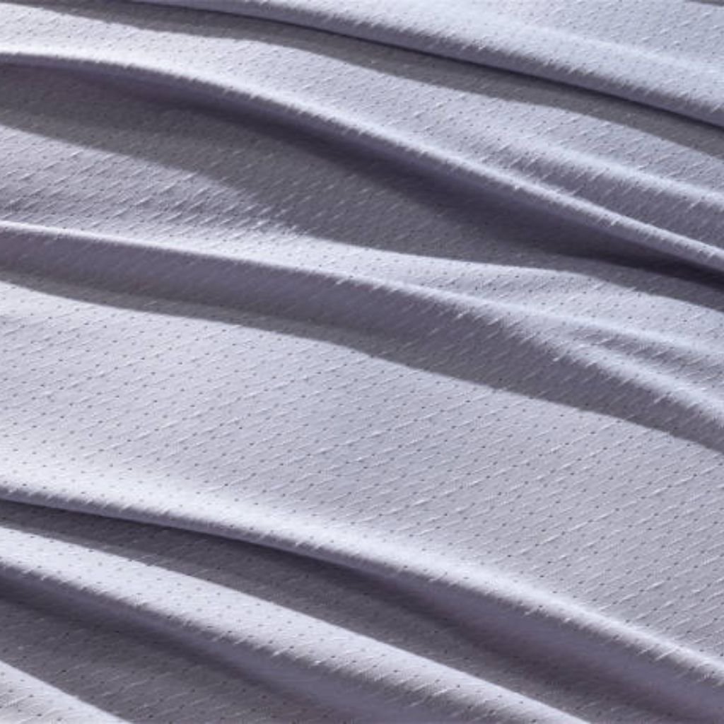 "Close-up of draped light purple fabric with a subtle dotted texture and soft folds forming a gentle wave-like pattern."
Chill Pro Moisture-Wicking Fabric Explained:
