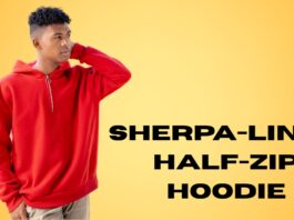 A young man wearing a red sherpa-lined half-zip hoodie stands against a warm yellow gradient background. He is touching the back of his head with one hand, looking to the left.