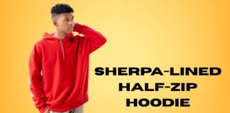 Sherpa-Lined Half-Zip Hoodie: Cozy Winter Essential A young man wearing a red sherpa-lined half-zip hoodie stands against a warm yellow gradient background. He is touching the back of his head with one hand, looking to the left.