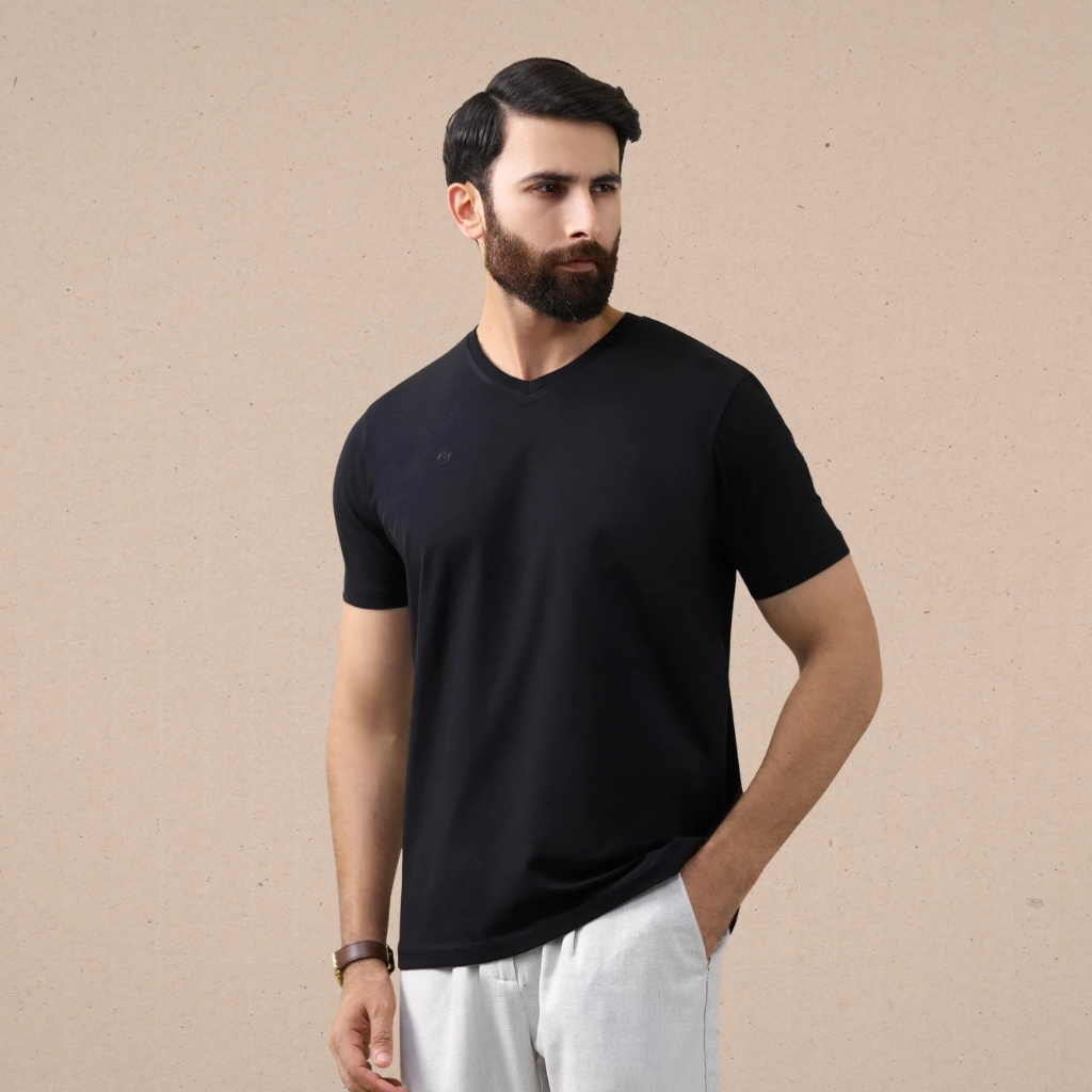 What Is a T-Shirt , Types and Style Guide 12 Man modeling a black v-neck t-shirt paired with light gray pants, shown against a neutral background.