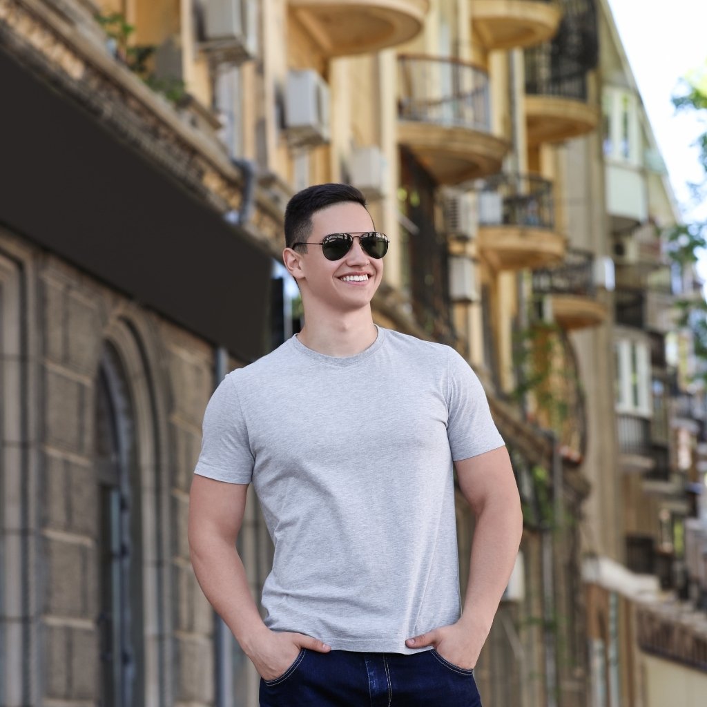 Man wearing a core style crew-neck t-shirt and dark sunglasses outdoors in a narrow alley.

