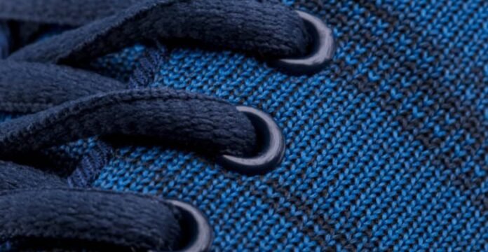 Blue shoelaces laced through a textured blue knitted fabric with dark horizontal stripes. Dynamic Flex Sports Knit: