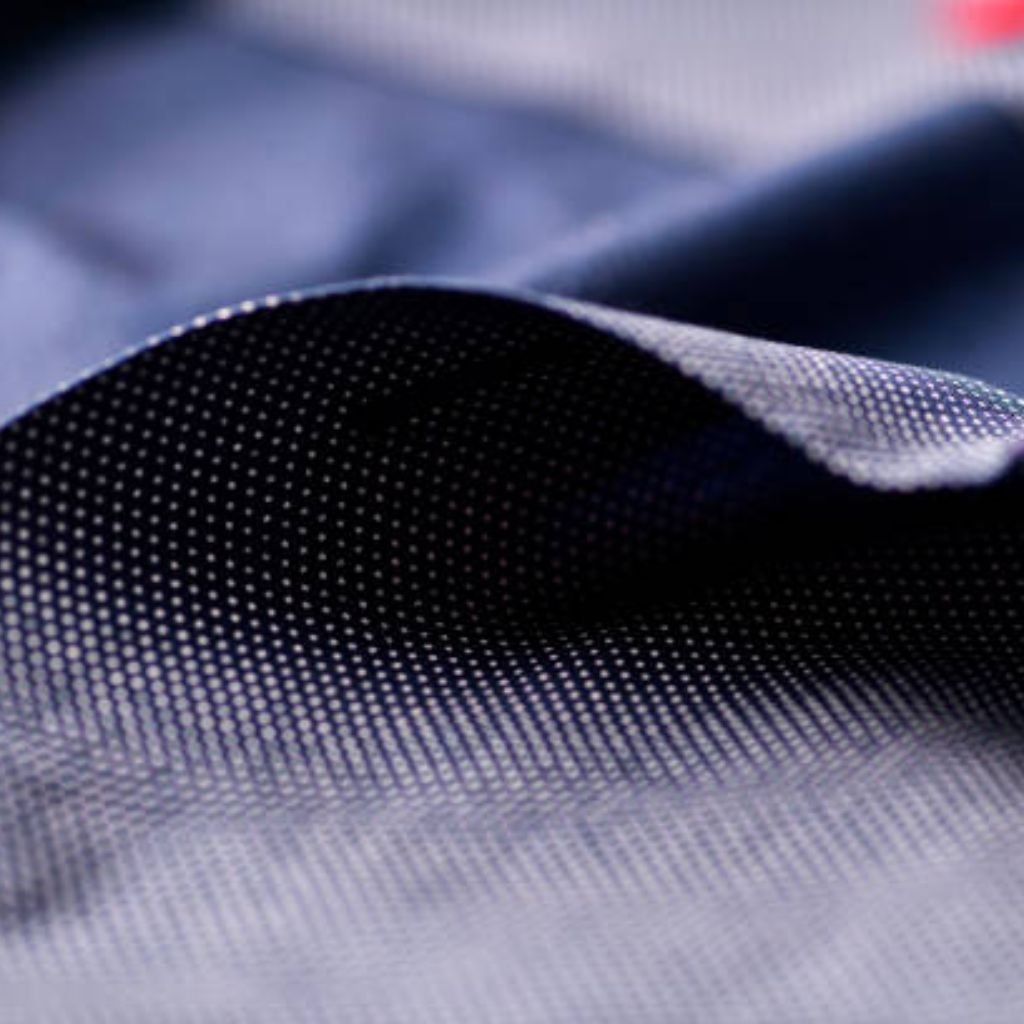 Neo Dry Tech Fabric: Ultimate Moisture Control for Athletes 9 Blue-and-white geometric weave fabric close-up, showing raised textured surface, tonal contrast between deep navy ground and crisp white dot motif, and dimensional folds revealing subtle ribbing and soft drape.
Neo Dry Tech Fabric: