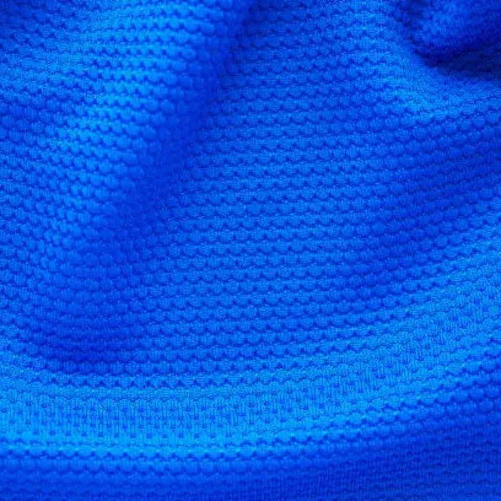 "Close-up of vivid blue sportswear fabric with a tactile, raised dot texture creating subtle folds and dimensional shadows under even lighting."
Aqua Lock Sports Knit:
