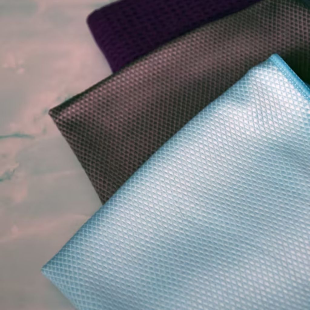 Three folded microfiber cloths in purple, dark gray, and light blue, each showing a visible waffle-textured surface on a mottled background.

Infinity Cool Tech Knit: