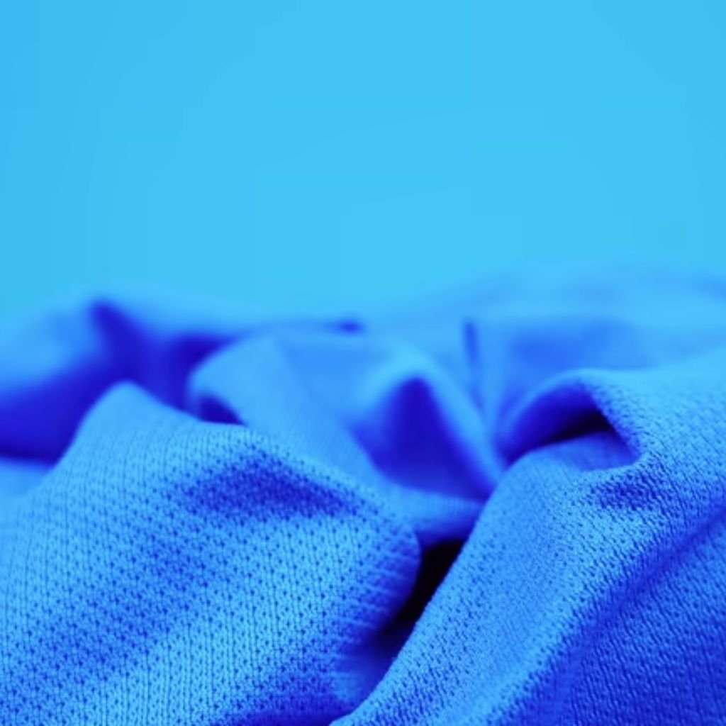 Close-up of textured bright blue athletic fabric with a fine perforated pattern, crumpled to show depth and breathability — used in military-inspired winter jackets.
Turbo Dry Athletic Fabric:
