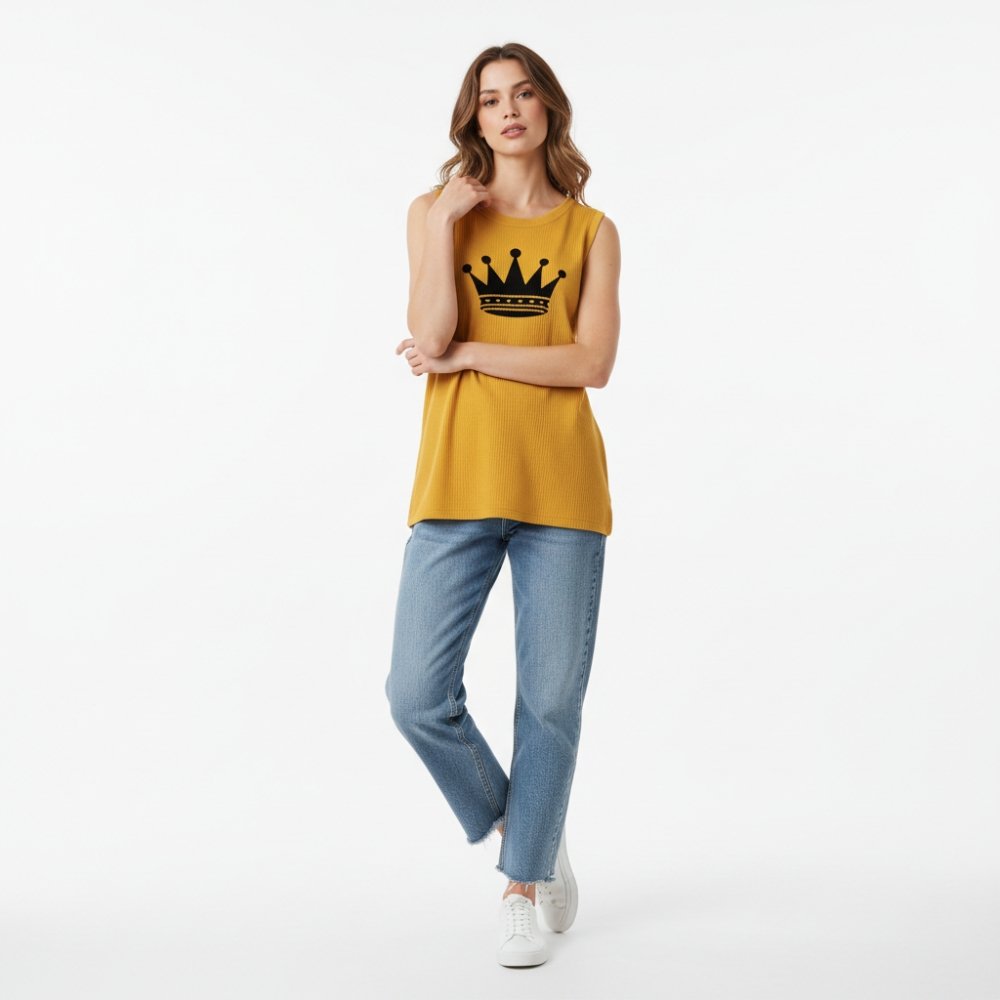 Top Trending Sleeveless T-Shirts That Redefine Comfort 8 Woman wearing a mustard yellow Sleeveless T-Shirts graphic knit top and light blue jeans with white sneakers.