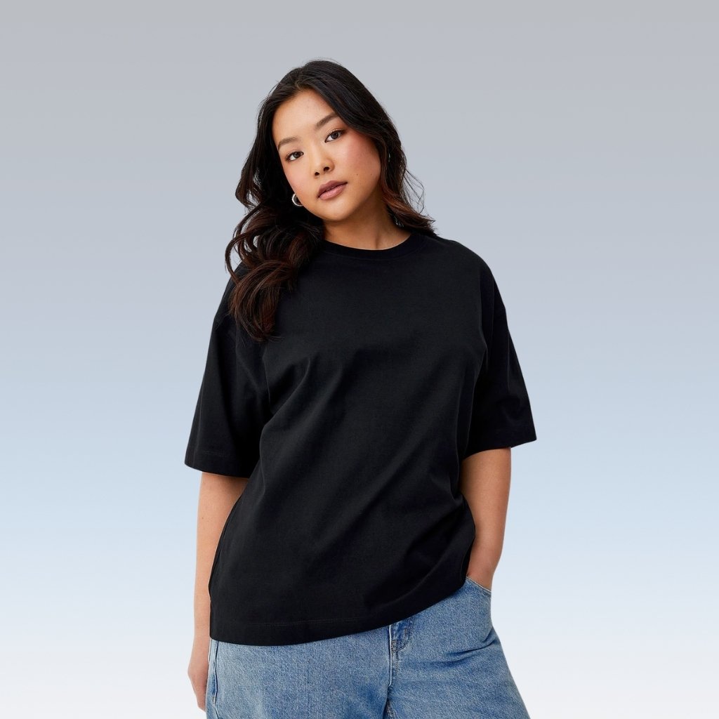 Model wearing a plain black crew-neck t-shirt paired with light blue jeans against a light gray background.

