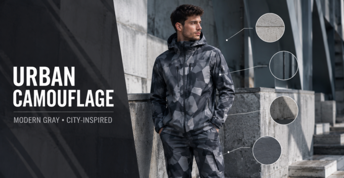 Model wearing gray urban camouflage clothing among concrete and steel city structures.