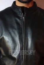 A close-up view of a young man's neck and chest area in a black leather jacket featuring a zip closure against a white background.